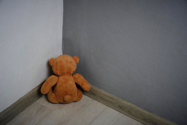 Teddy bear soft toy sitting corner roomConcept of domestic violence against children