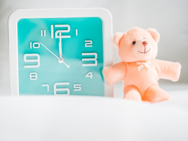 Photo teddy bear toy and clock in the bedroom.