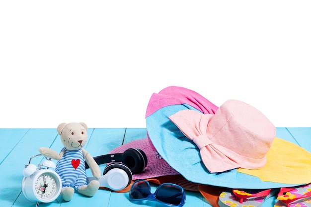 teddy bear with alarm clock and summer accessories on blue wood.