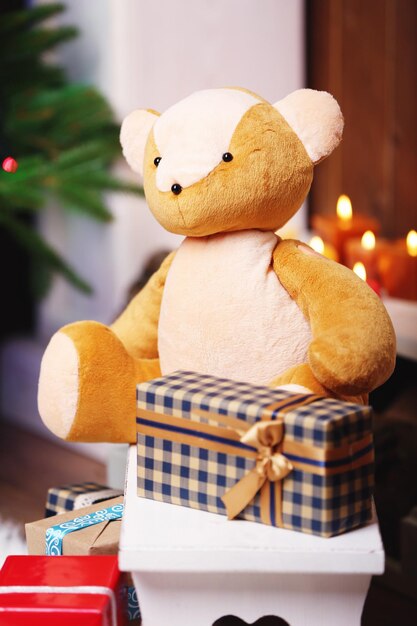 Teddy bear with Christmas gifts in room