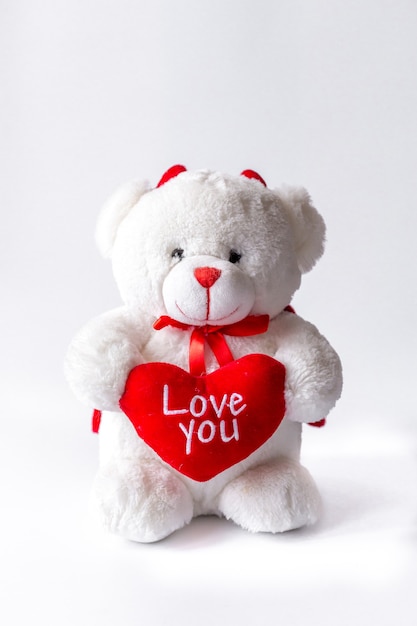 Teddy bear with heart in hand on white background