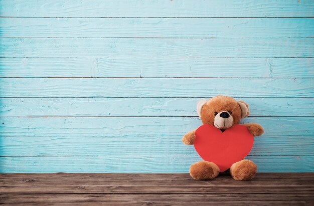 Teddy bear with red heart on old wooden surface