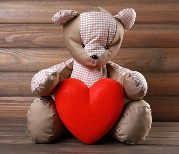 Teddy Bear with red heart on wooden background