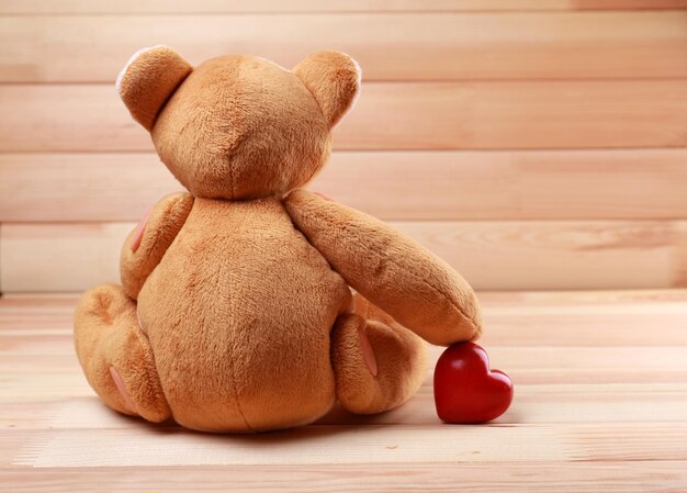 Teddy Bear with red heart on wooden background