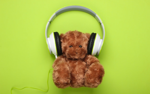 Teddy bear with stereo headphones on a green surface