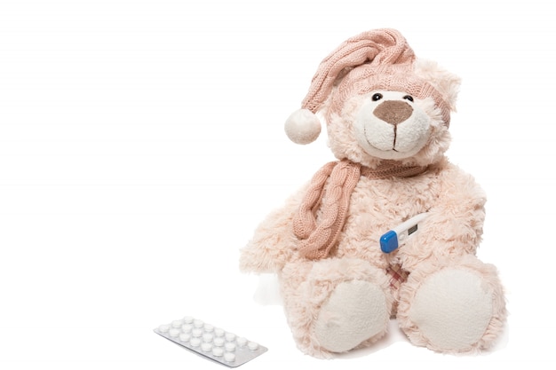 Teddy bear with a thermometer and pills