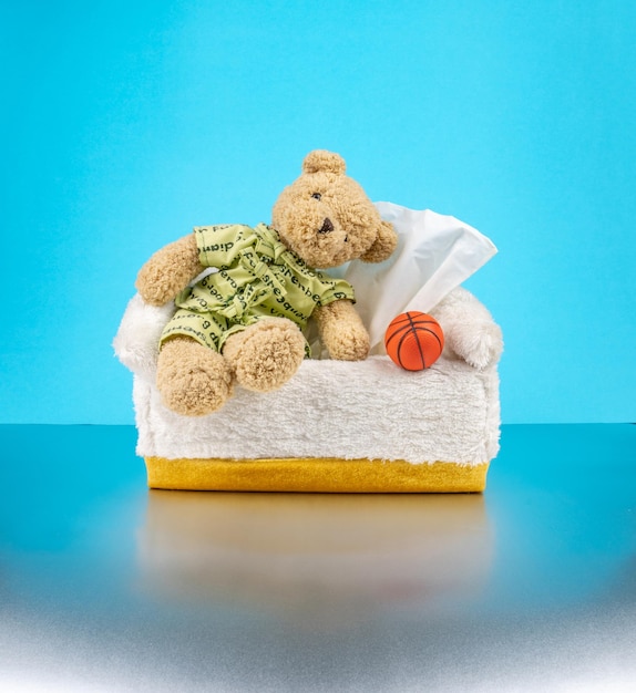 Teddybeer draagt de pyjama en zit op de tissuedoos met basketbal ernaast