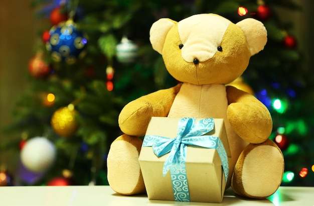 Teddybeer en geschenkdoos op kerstboomachtergrond