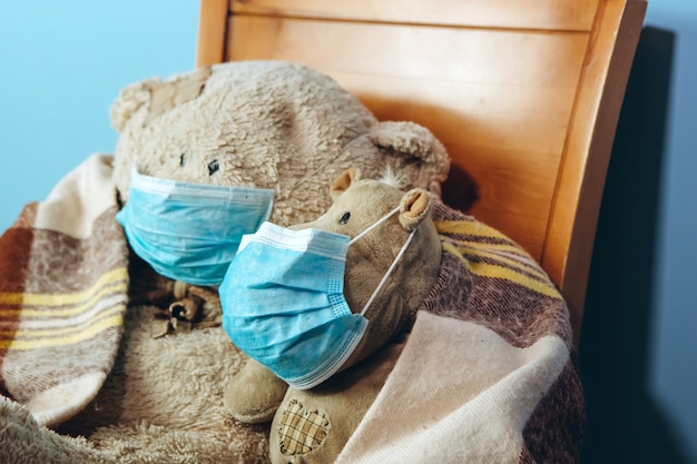 Teddybeer en nijlpaard in een medisch masker op een blauwe muur. Concept van 2019-20 coronavirus Covid-19 pandemie.