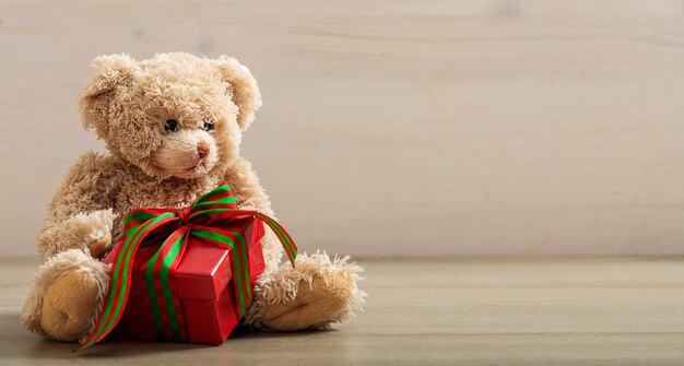 Teddybeer houdt een geschenk vast op een houten vloer