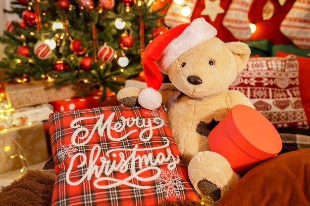 Teddybeer in kerstmuts met geschenkdoos in onscherpe achtergrond vrolijk kerstfeest