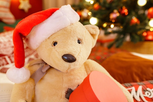 Teddybeer in kerstmuts met geschenkdoos in wazige achtergrond vrolijk kerstfeest