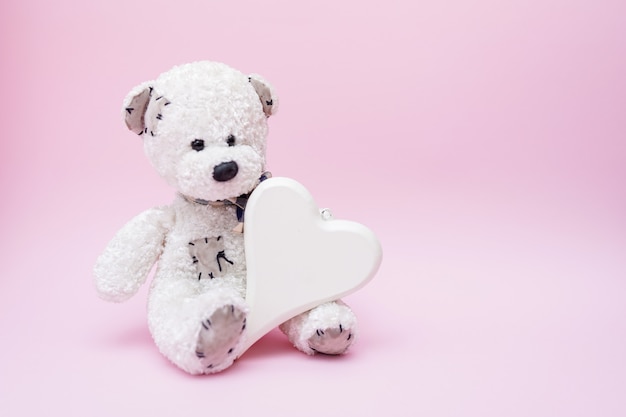 Teddybeer met liefdehart op roze achtergrond, kopie ruimte