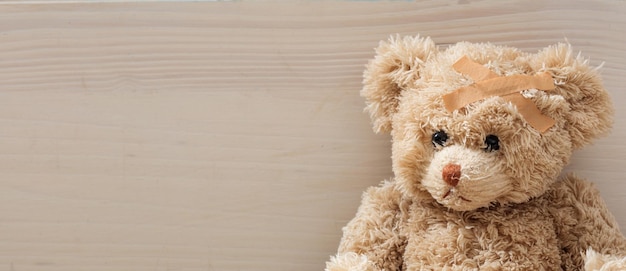 Teddybeer met verband op een houten vloer