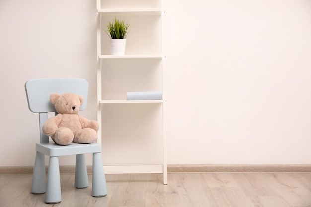 Teddybeer op stoel en plank bij muur in kinderkamer Ruimte voor tekst