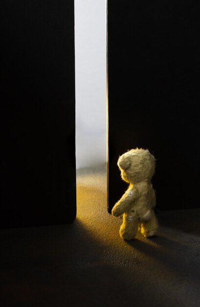 Foto teddybeer voor een open deur licht door de deuropening conceptuele foto over kindertijd dre