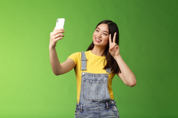 Tedere schattige Aziatische brunette vrouw houden smartphone poseren selfie kijken telefoon scherm fotograferen ...