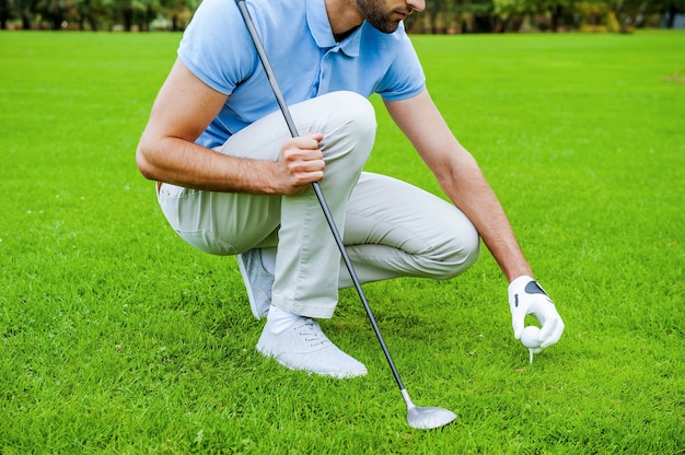 Teeing up. Close-up of golfer placing a golf ball on tee prior