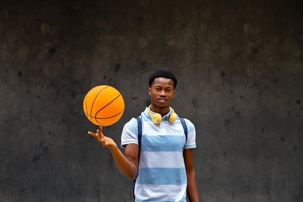 Teen african american boy spinning basketball ball on finger\
looking at camera copy space