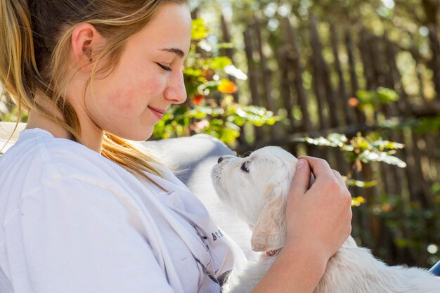 英語のゴールデンレトリーバーの子犬を保持している 10 代の少女