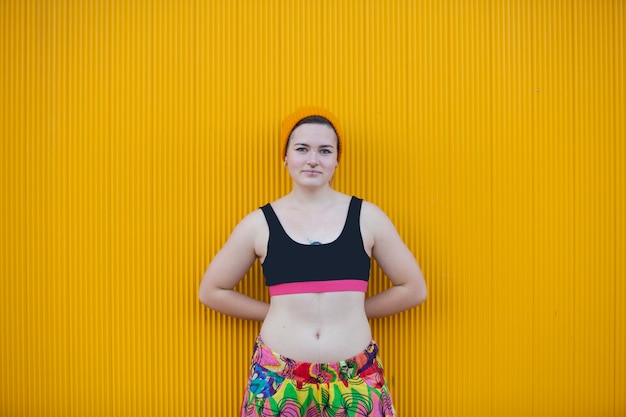 Teen androgynous woman on a yellow wall