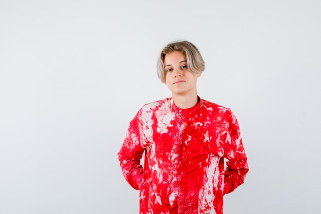 Teen blonde male with hands behind back in oversize shirt and looking confident. front view.