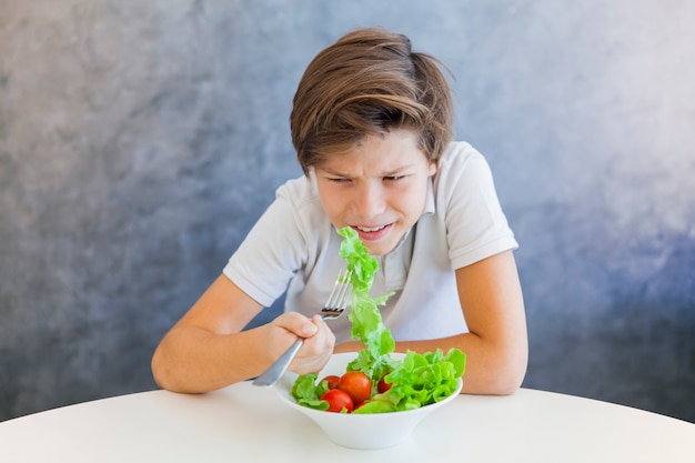 Teen boy eating salad unhappy