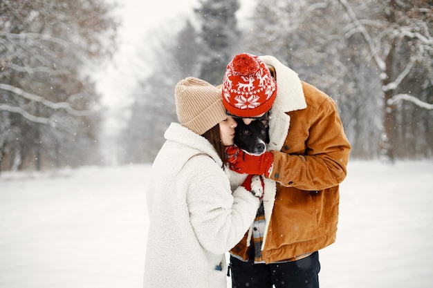 Teen boy and girl with their cute black dog standing at winter park