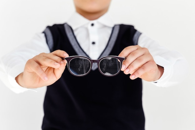 Teen boy holds eyeglasses in hands in front of himself. Children, ophthalmology and healthcare concept