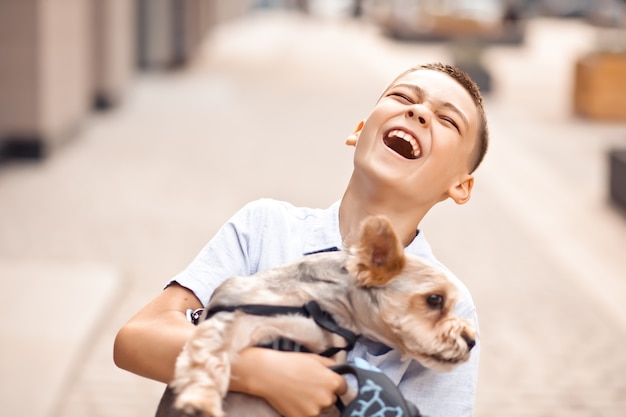 公園で屋外の手で保持しているペットの動物の小さな犬と10代の少年の子供。