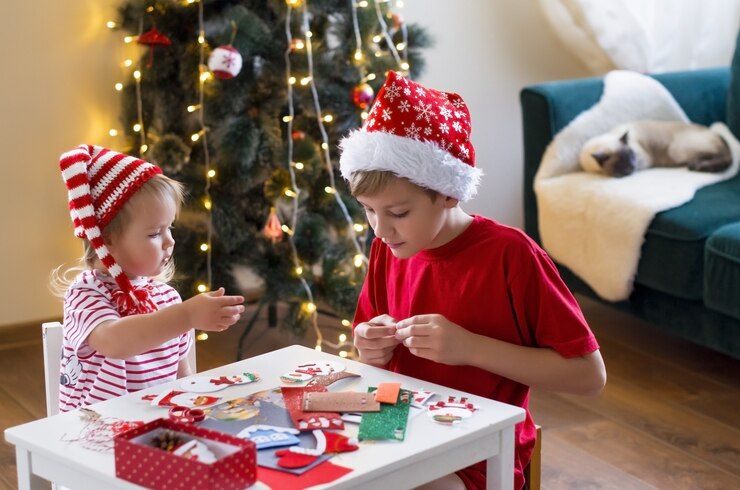 Photo teen boy and little girl in santa hat making decorations for christmas