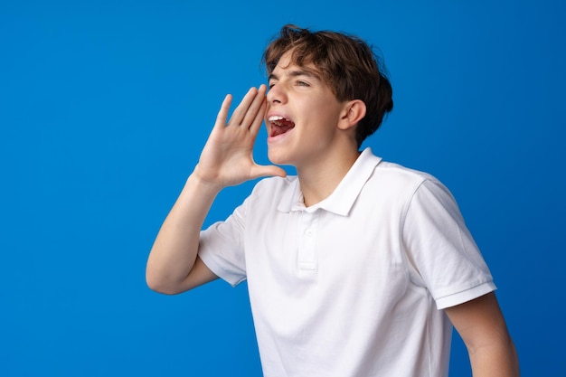 Teen boy making loud announcement against blue background