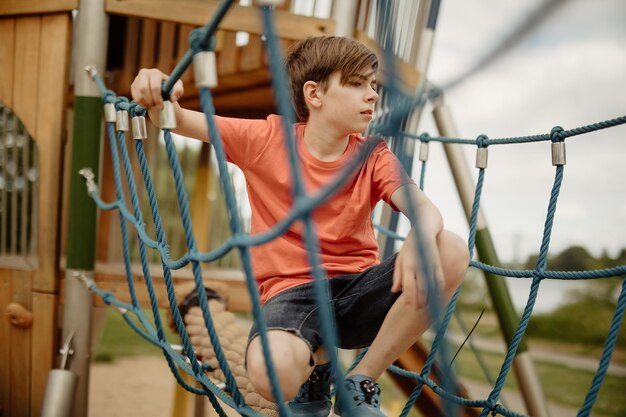 Teen boy rest at playground rope watch out for other kids and\
have thoughts while having a mean idea