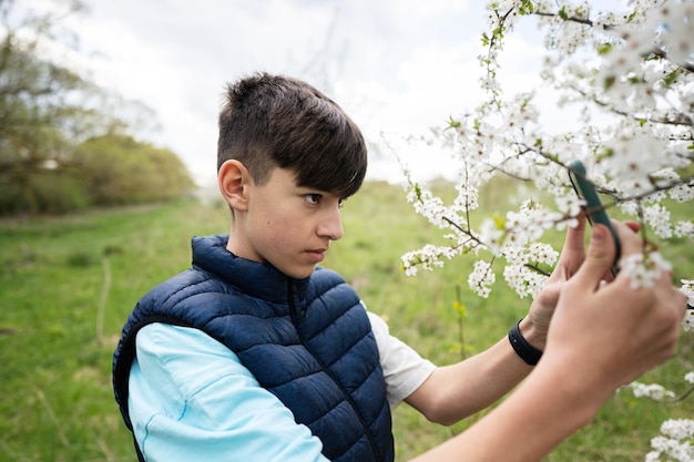 Teen boy takes a photo of a flowering tree on his phone