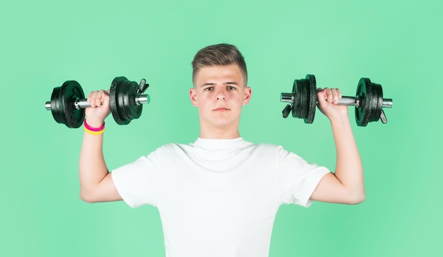 Teen boy training biceps muscles with barbell sport