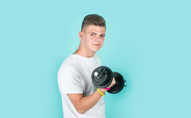 Teen boy training biceps muscles with barbell sport