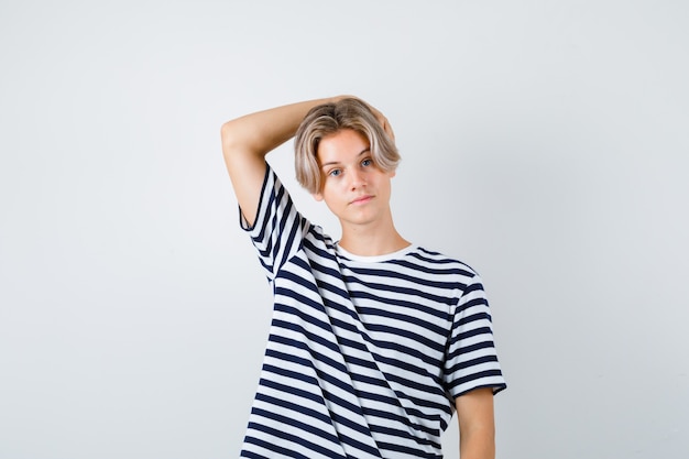 Teen boy with hand on head in t-shirt and looking confident. front view.