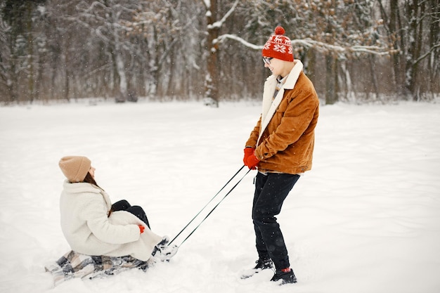 Teen brother and sister riding a sled at winter park