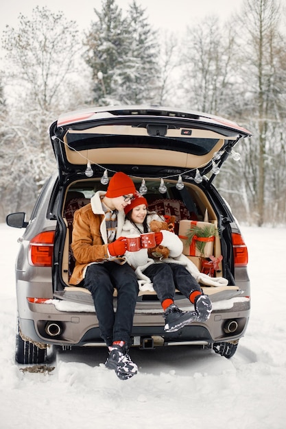 Teen brother and sister sitting in open car's trunk at winter park