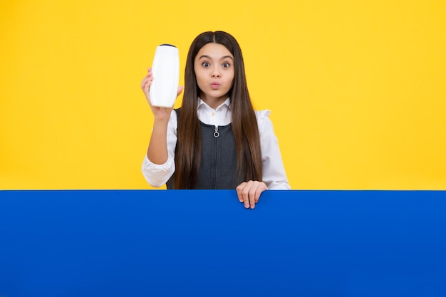 Teen child girl with shampoo bottle or shower gel isolated on yellow background Kids hair cosmetic