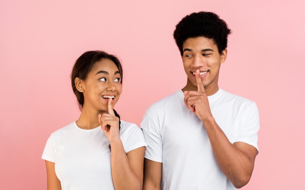 Teen couple make silence sign keep forefingers on lips