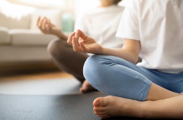 Teen european girl and millennial woman in sportswear sit in lotus position on mat meditate practice