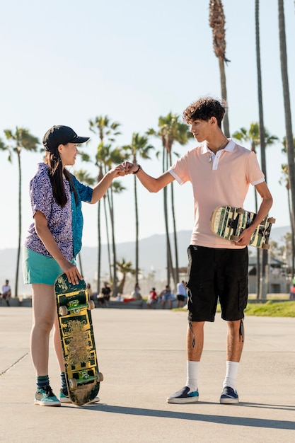 Amici adolescenti pugno di pugno, pattinatori a venice beach, los angeles