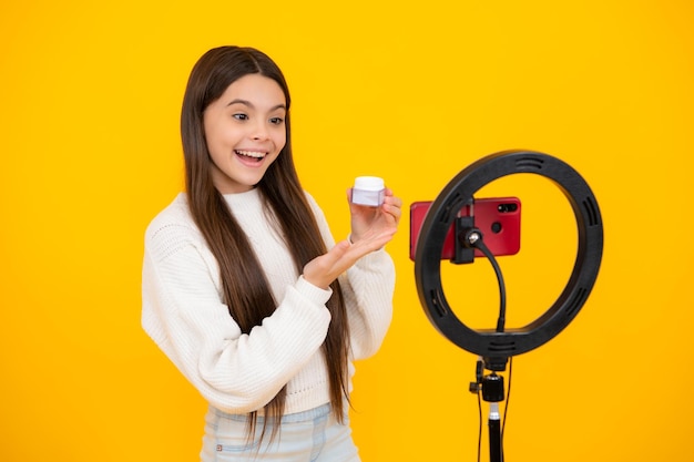 Teen girl blogger influencer use selfie led lamp and smartphone on tripod for making online video