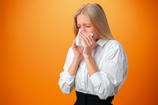 Teen girl blowing her nose against orange background