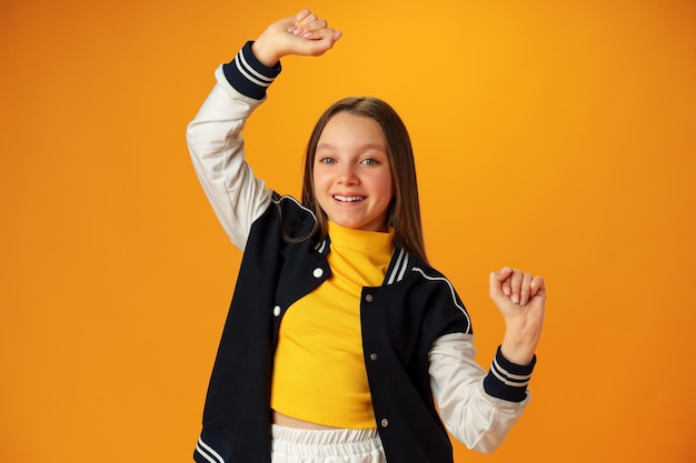 Teen girl dancing against yellow studio background