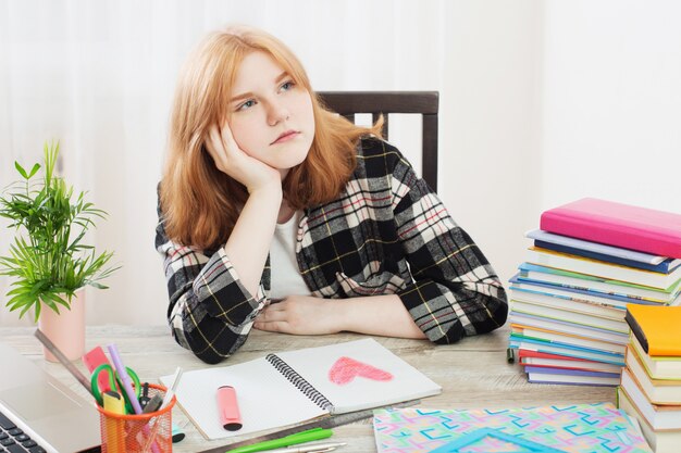 Teen girl draws  heart in  notebook, concept of first love