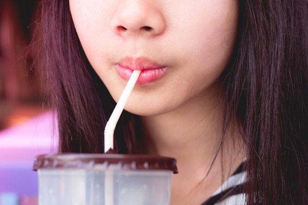 Ragazza teenager che beve puro dall'acqua succhiando staw.