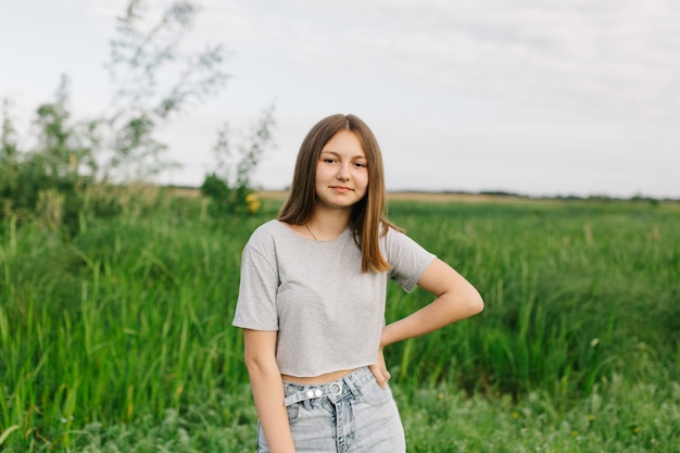 teen girl in gray tshirts and gray jeans on the green grass Nature walk in summer summer vacation