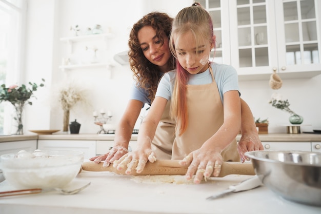 Ragazza teenager che aiuta sua madre a cucinare la pasta nella loro cucina a casa